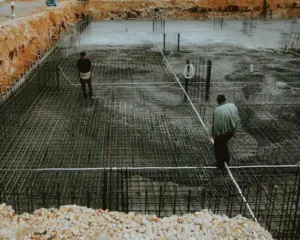 Ground Reinforcement with Ocean Biaxial Geogrid - Two workers inspecting a rebar grid foundation at a construction site.