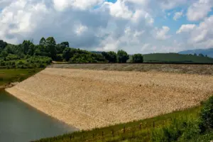 Riverbank Protection and Irrigation Stability Using - Tranquil rural landscape featuring a dam and lush greenery under a brig