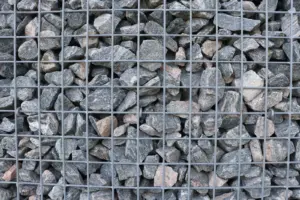 Holding the River Steady: Ocean Double-Twisted - Detailed view of a gabion wall filled with natural stones arranged tightly.
