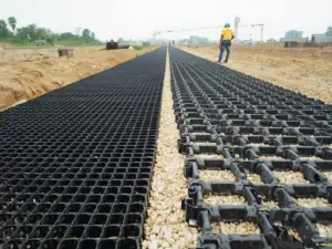 Gravel-filled HDPE geocell beside flat biaxial geogrid on a road formation