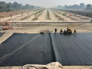 Crew welding thick black HDPE liner panels across a graded basin on grey ash ground in Delhi